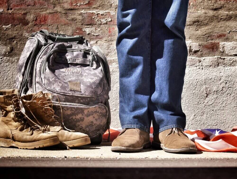 veteran standing next to boots and backpack